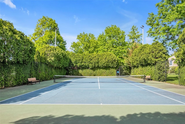 view of tennis court featuring community basketball court and fence