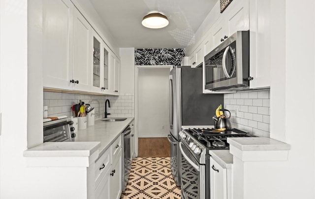 kitchen featuring appliances with stainless steel finishes, a sink, white cabinets, and light countertops
