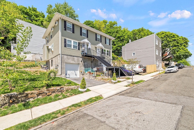 multi unit property featuring stairway, a garage, and asphalt driveway