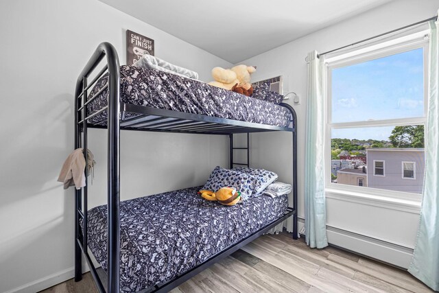 bedroom featuring baseboard heating and wood finished floors