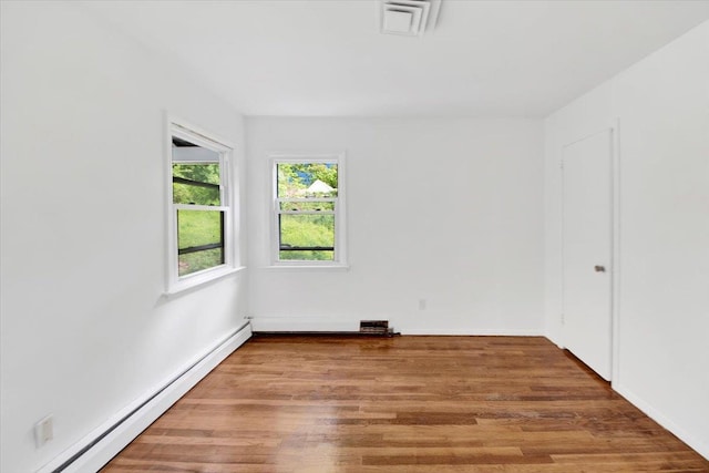 spare room with a baseboard radiator, wood finished floors, and baseboards