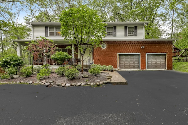 view of front facade featuring asphalt driveway, covered porch, and brick siding