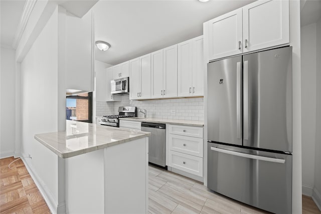 kitchen featuring stainless steel appliances, white cabinetry, backsplash, light stone counters, and a peninsula