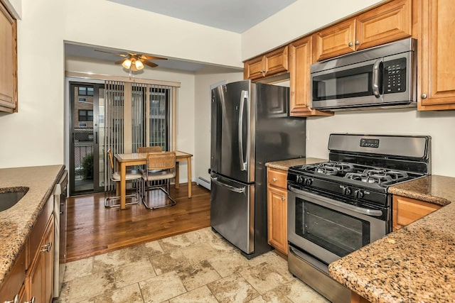 14 Florence Unit 25D, Freeport, NY 11520 - kitchen with stainless steel appliances, ceiling fan, light stone finish flooring, light stone countertops, and a baseboard radiator