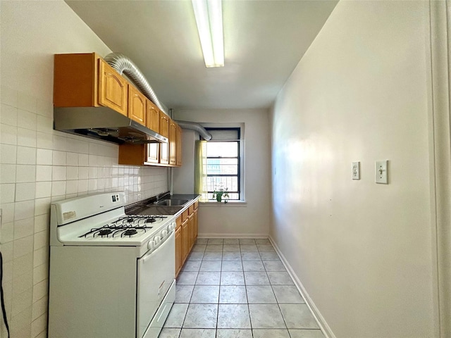 62-64 Saunders St Unit 3H, Rego Park, NY 11374 - kitchen featuring gas range gas stove, a sink, under cabinet range hood, light tile patterned floors, and backsplash