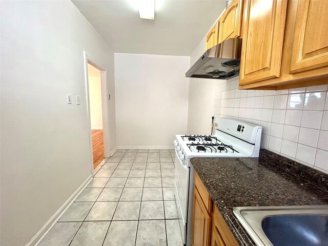 62-64 Saunders St Unit 3H, Rego Park, NY 11374 - kitchen with range hood, white range with gas stovetop, decorative backsplash, light tile patterned floors, and dark stone counters