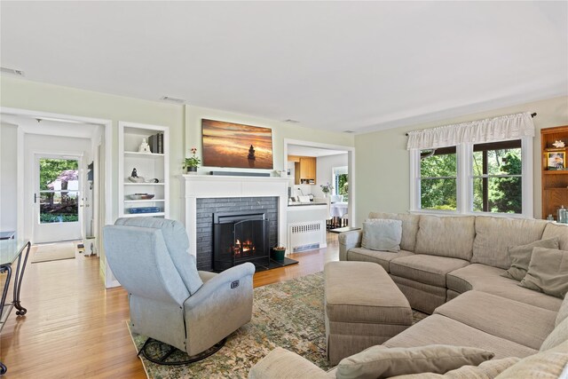 3 Summit Dr, Baiting Hollow, NY 11933 - living room with radiator, healthy amount of natural light, light wood finished floors, and a brick fireplace
