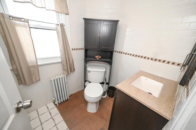 half bath featuring radiator heating unit, tile walls, toilet, vanity, and tile patterned floors