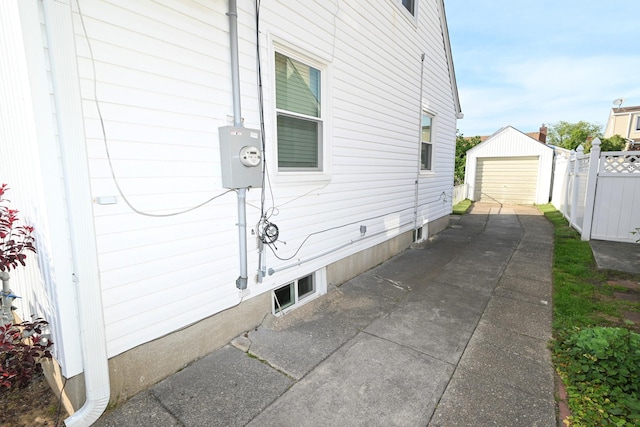 view of home's exterior featuring fence, driveway, and an outbuilding