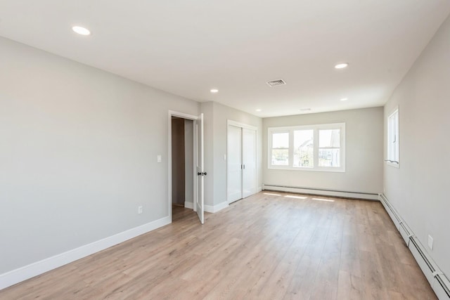 spare room with baseboard heating, light wood-type flooring, recessed lighting, and baseboards