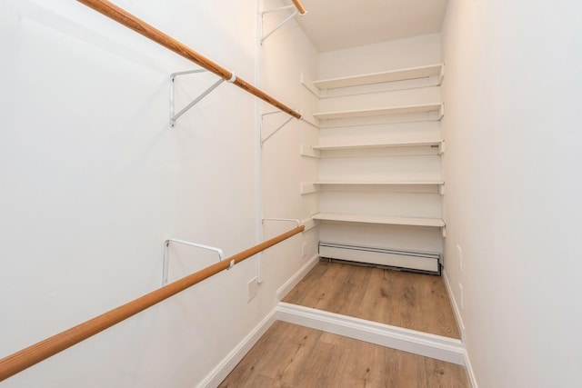 spacious closet featuring baseboard heating and wood finished floors