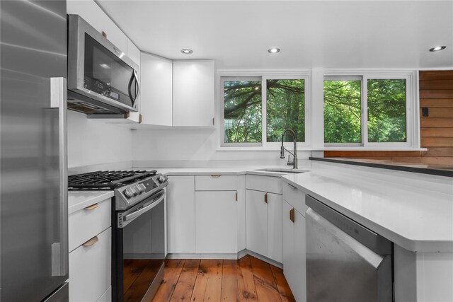 14 Lounsbury Rd, Croton-On-Hudson, NY 10520 - kitchen with appliances with stainless steel finishes, a sink, white cabinets, light countertops, and hardwood / wood-style floors