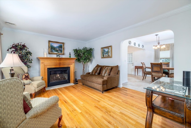 19 Croyden St, New Hyde Park, NY 11040 - living area featuring arched walkways, a chandelier, crown molding, a glass covered fireplace, and light wood finished floors