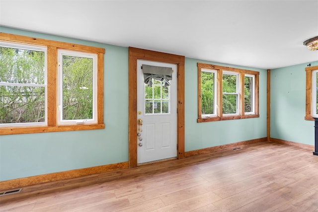 doorway to outside featuring light wood-type flooring, baseboards, and healthy amount of natural light