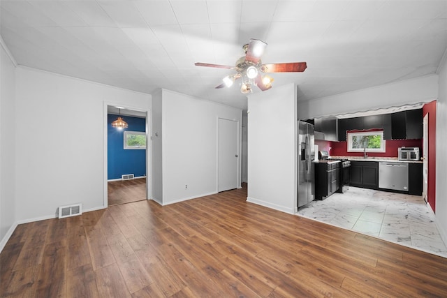 unfurnished living room featuring ceiling fan, light wood finished floors, a sink, and baseboards