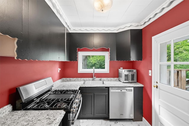 kitchen featuring stainless steel appliances, a sink, and light stone counters