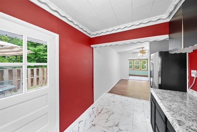 kitchen featuring ceiling fan, light marble finish flooring, and baseboards