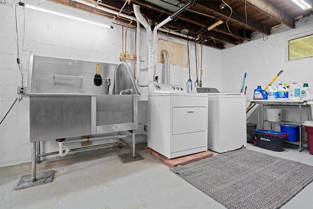 laundry room featuring washing machine and dryer, concrete block wall, and pet washing area