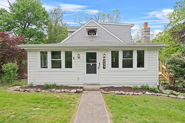 view of front of property with a front lawn, a chimney, and roof with shingles