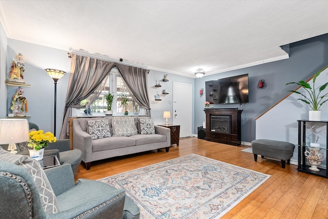 living room featuring hardwood / wood-style floors, crown molding, and a glass covered fireplace