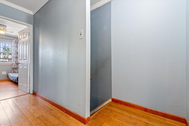 corridor with wood-type flooring, crown molding, and baseboards