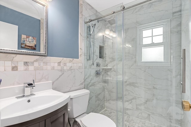 bathroom featuring toilet, a stall shower, vanity, a wainscoted wall, and tile walls