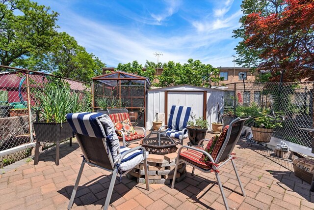 view of patio with a fire pit, a storage unit, a fenced backyard, and an outdoor structure