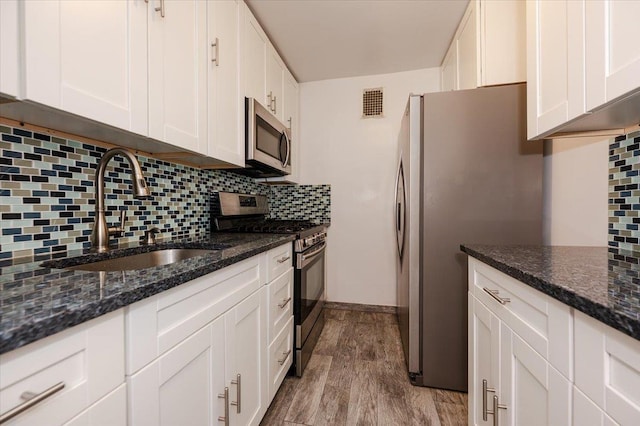 85-10 151st Ave Unit 5E, Howard Beach, NY 11414 - kitchen featuring stainless steel appliances, a sink, white cabinetry, tasteful backsplash, and wood finished floors