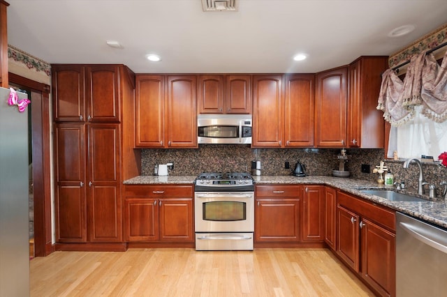 251 N Idaho Ave, Massapequa, NY 11758 - kitchen featuring appliances with stainless steel finishes, a sink, light wood finished floors, stone counters, and backsplash