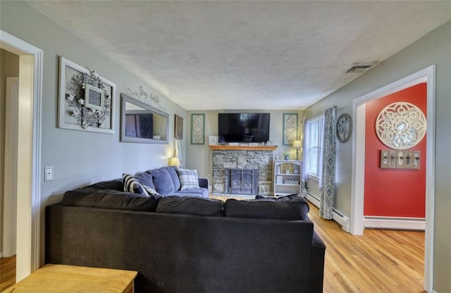 1547 Rte 208, Washingtonville, NY 10992 - living room with light wood-type flooring, baseboard heating, a fireplace, a textured ceiling, and baseboards