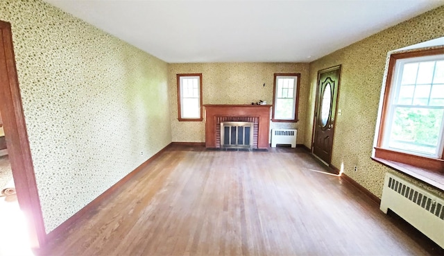 233 Peaceable Hill Rd, Brewster, NY 10509 - unfurnished living room featuring radiator heating unit, wood finished floors, a fireplace, and wallpapered walls