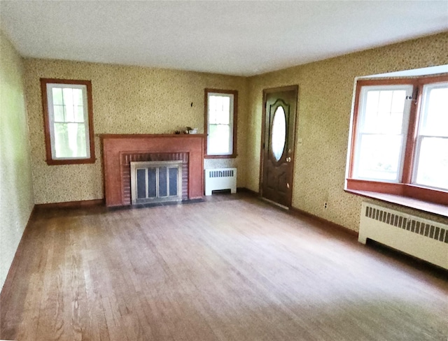 233 Peaceable Hill Rd, Brewster, NY 10509 - unfurnished living room with radiator, a brick fireplace, and wallpapered walls