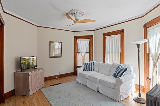 604 Main St, Greenport, NY 11944 - living room featuring baseboards, light wood-type flooring, crown molding, and ceiling fan