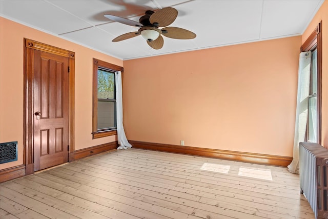 604 Main St, Greenport, NY 11944 - empty room with radiator heating unit, baseboards, ceiling fan, light wood-style flooring, and crown molding