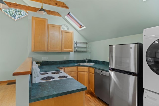 604 Main St, Greenport, NY 11944 - kitchen with stainless steel appliances, a skylight, a sink, stacked washing machine and dryer, and dark countertops