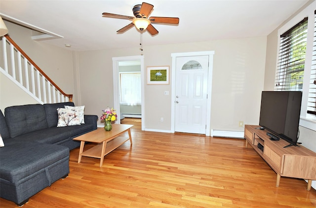 living room with a baseboard heating unit, light wood-style flooring, stairway, baseboard heating, and a ceiling fan