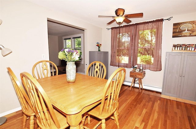 dining room featuring a baseboard heating unit, light wood-type flooring, and ceiling fan