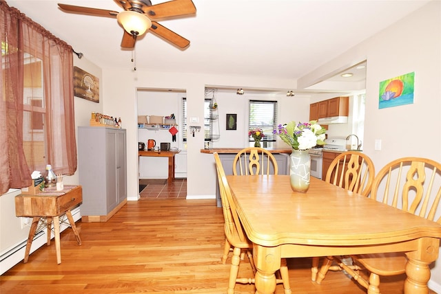 dining space with a ceiling fan, light wood-style flooring, a baseboard heating unit, and baseboards