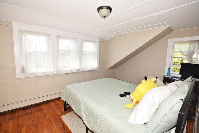 bedroom with wood finished floors, lofted ceiling, and a baseboard radiator