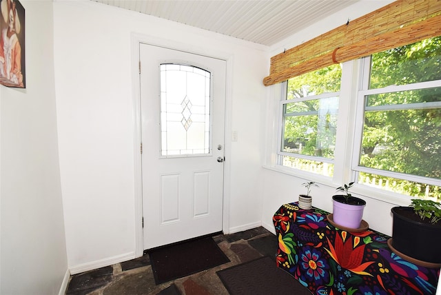 foyer with stone tile floors, plenty of natural light, and baseboards