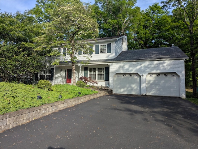 traditional home with an attached garage, asphalt driveway, and brick siding