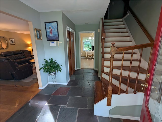 hallway with stone tile floors, stairway, and baseboards