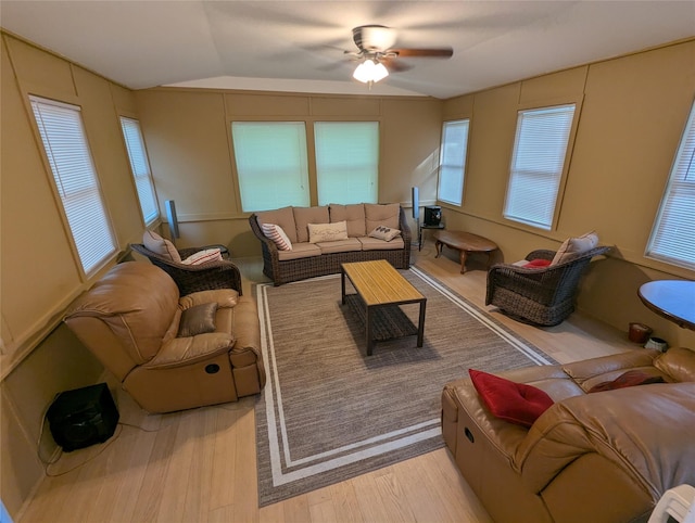 living area with lofted ceiling, wood finished floors, healthy amount of natural light, and a ceiling fan