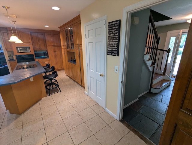 kitchen with stainless steel microwave, a kitchen bar, brown cabinets, recessed lighting, and dark countertops