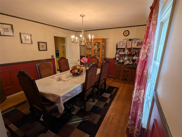 dining area with a chandelier, wainscoting, and wood finished floors
