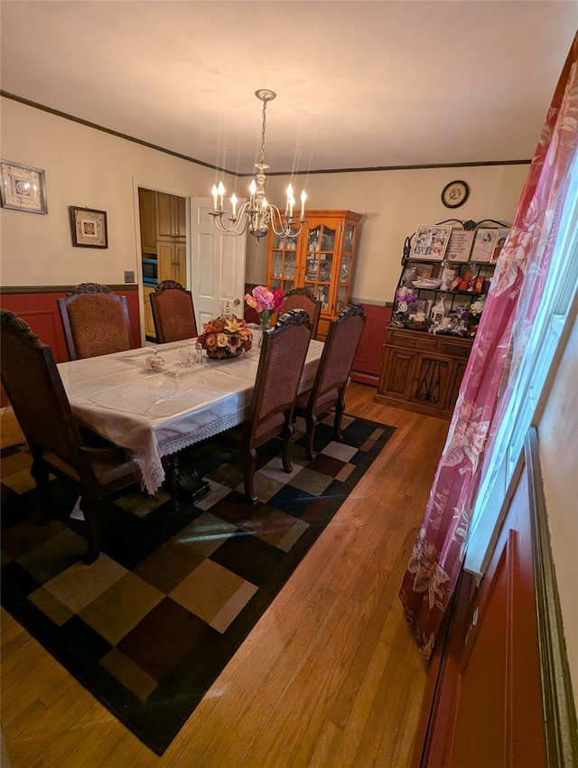 dining room with a chandelier, wainscoting, and wood finished floors