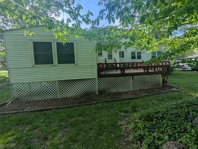 back of property with a wooden deck and a lawn