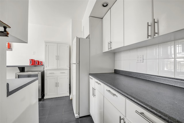 100-25 Queens Blvd Unit 6E, Forest Hills, NY 11375 - kitchen featuring freestanding refrigerator, white cabinetry, dark countertops, and dark tile patterned floors