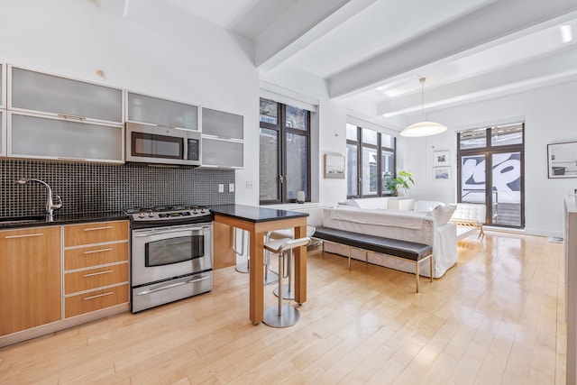 242 S 1st St Unit 1D, Brooklyn, NY 11211 - kitchen with appliances with stainless steel finishes, dark countertops, modern cabinets, beam ceiling, and decorative backsplash