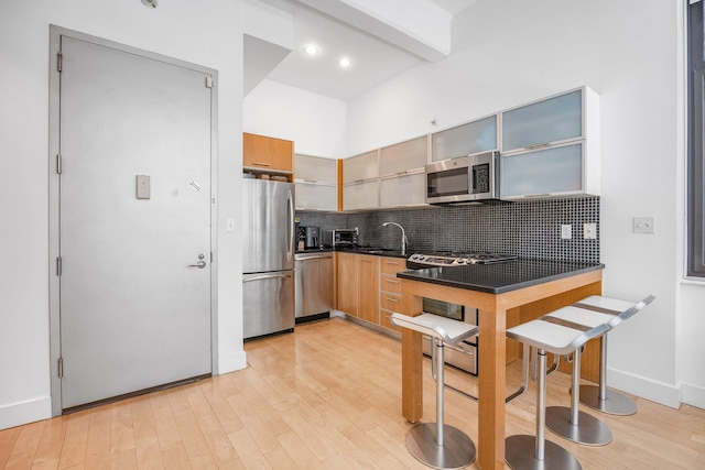 242 S 1st St Unit 1D, Brooklyn, NY 11211 - kitchen featuring stainless steel appliances, dark countertops, light wood finished floors, backsplash, and beam ceiling
